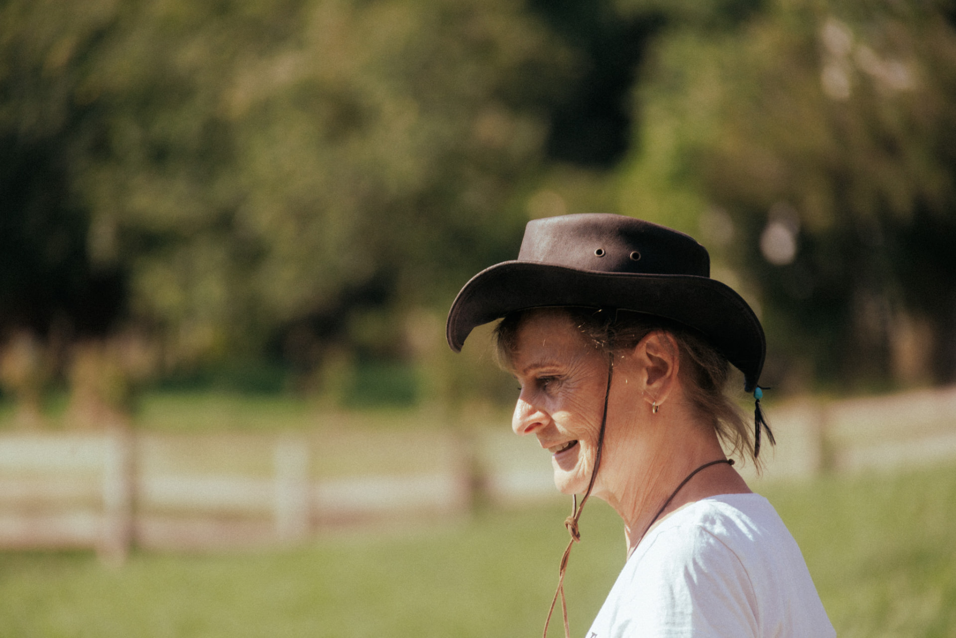 Ingrid Pockstaller lächelt im Profil mit Cowboyhut auf der Weide